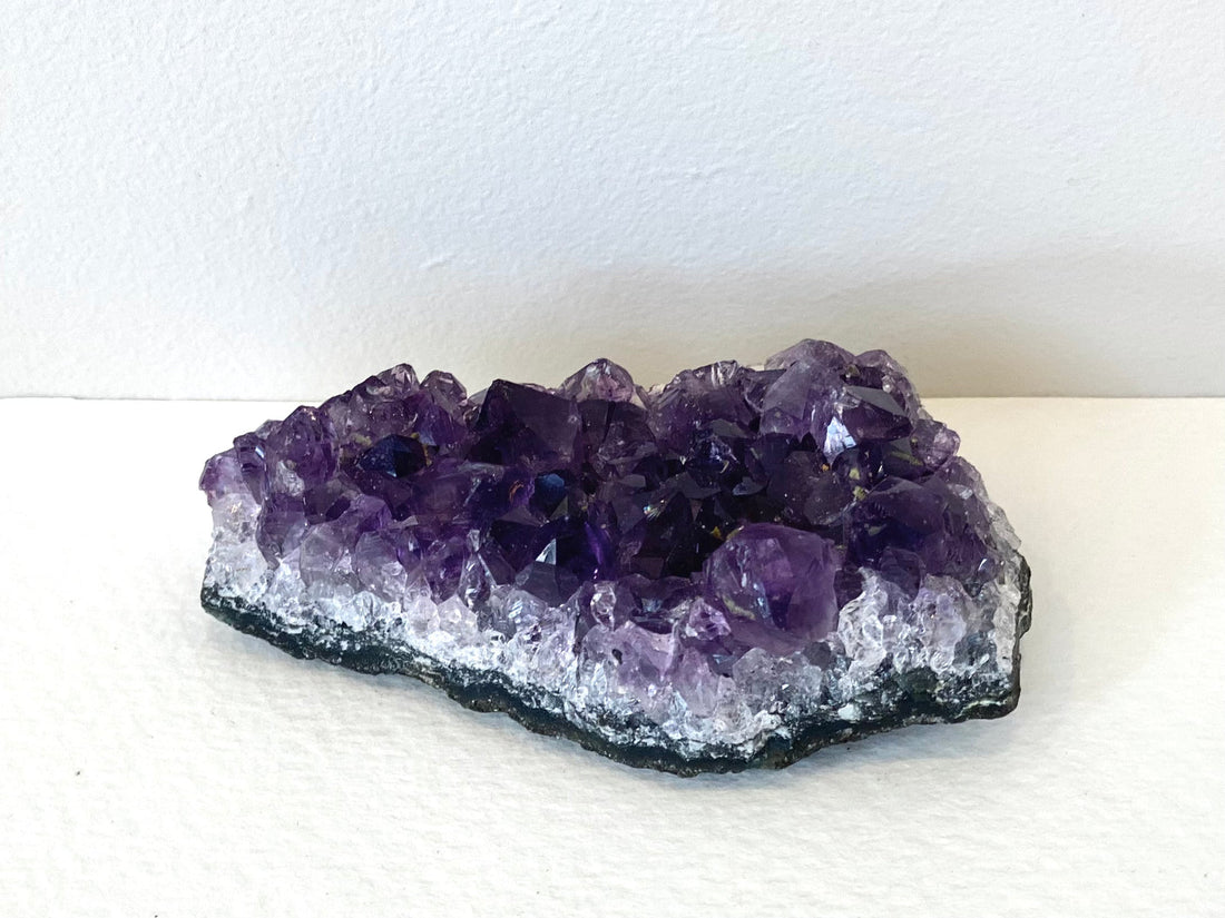 A small amethyst cluster with deep purple crystal points on a pale quartz base.