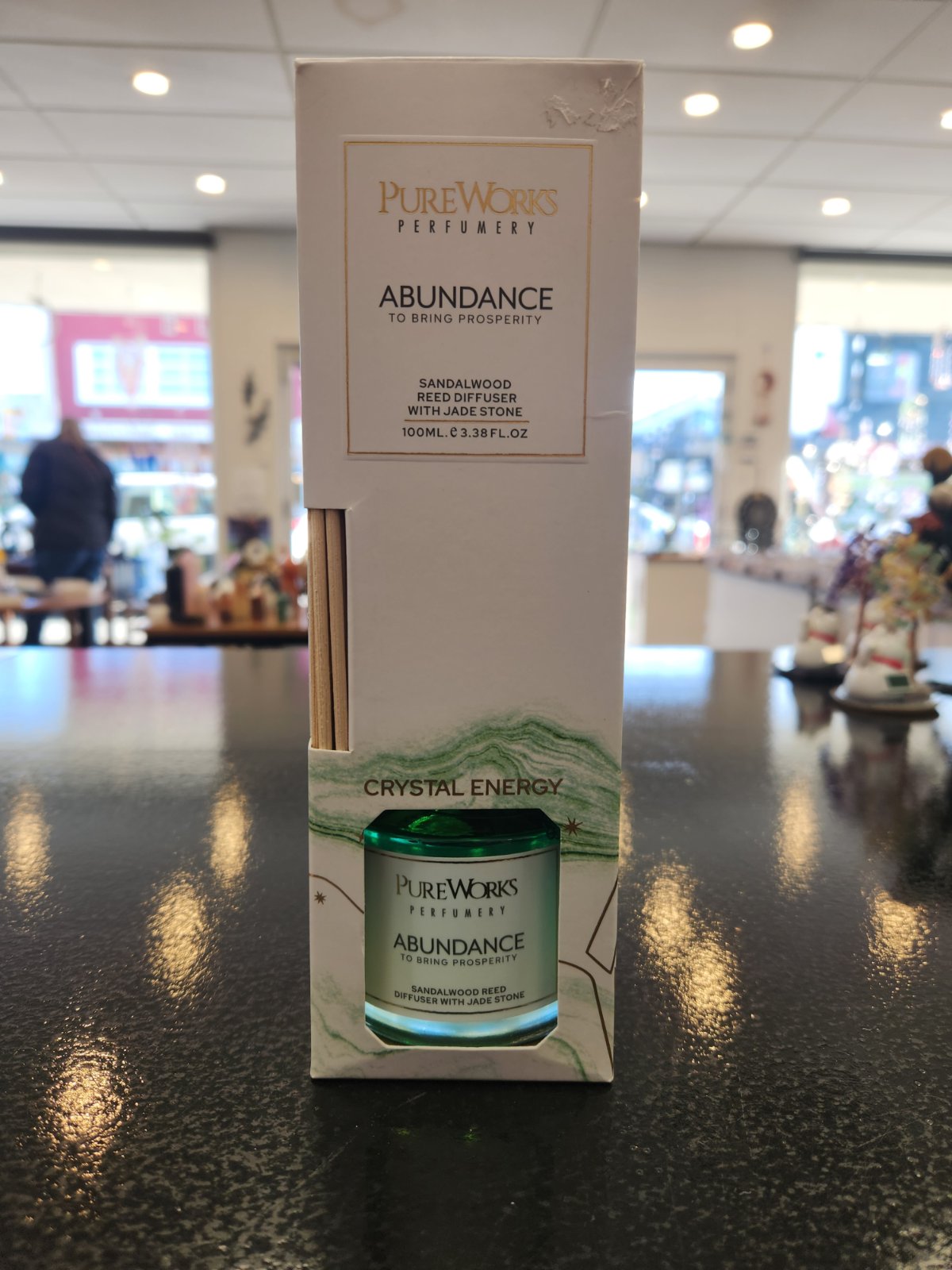 PureWorks Abundance Sandalwood Reed Diffuser with Jade Stone in white packaging displayed on counter