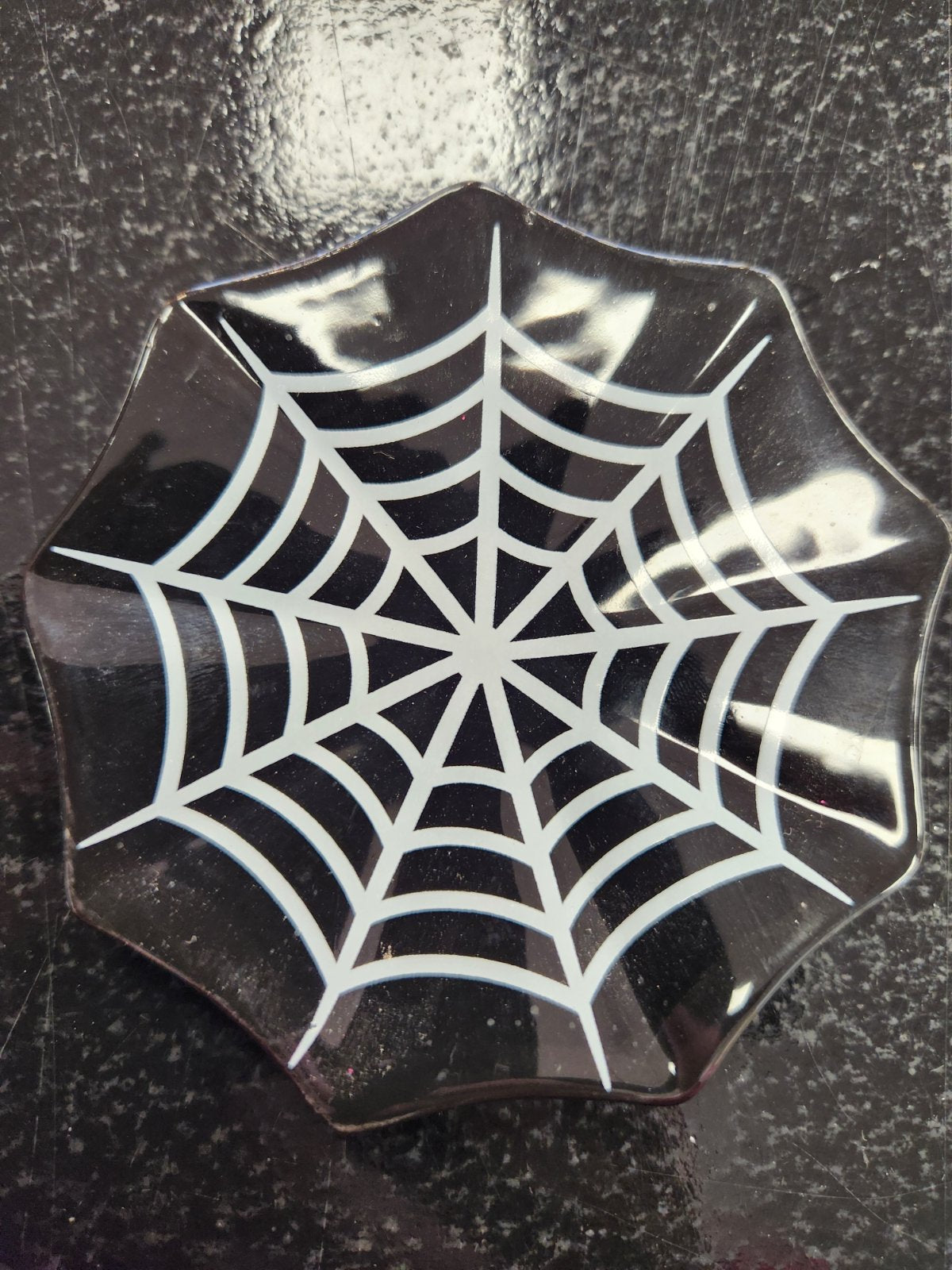 Black ceramic trinket dish with white spiderweb pattern design and scalloped wavy edges