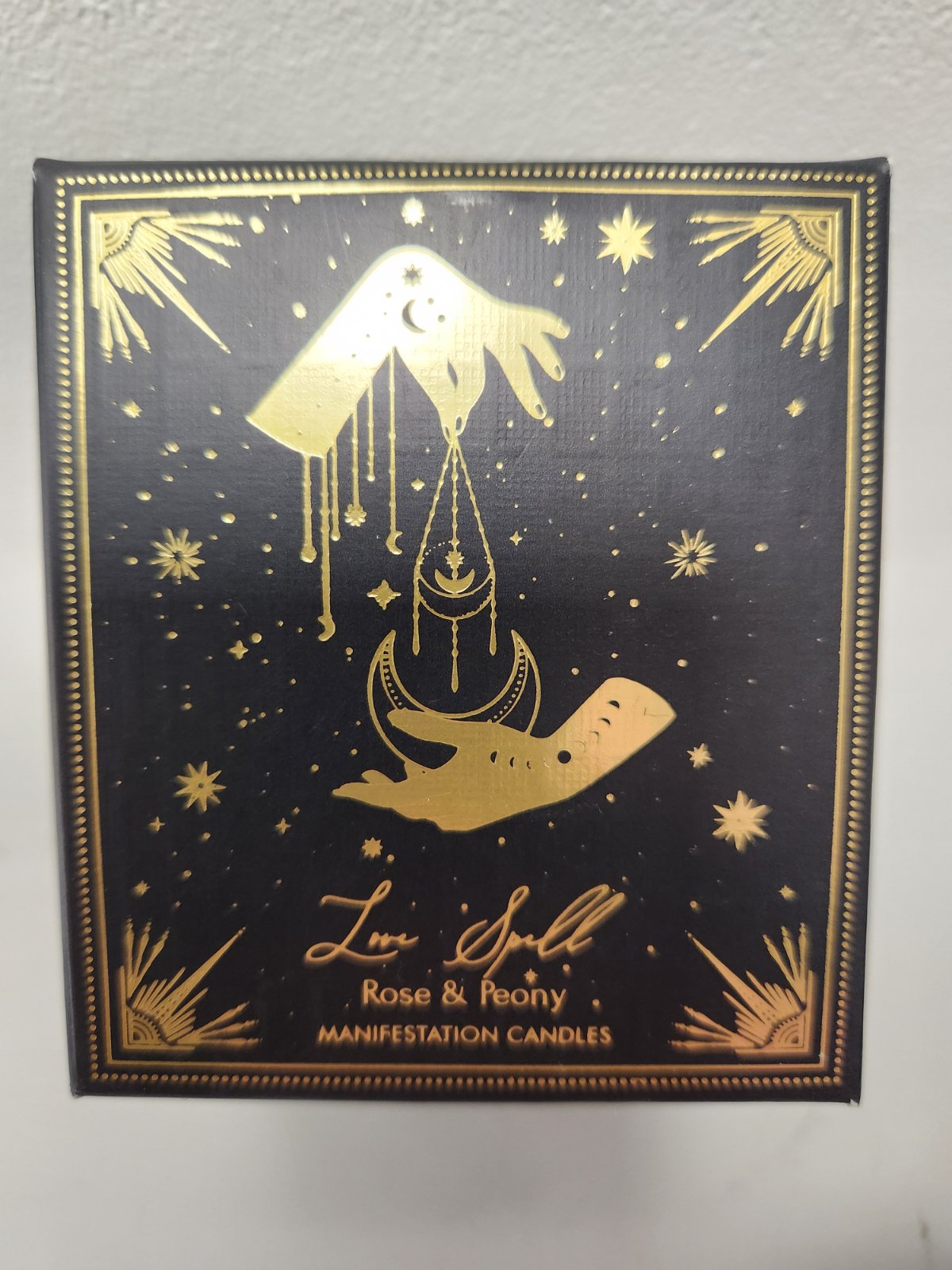 Black and gold Love Spell manifestation candle with mystical hand and celestial design