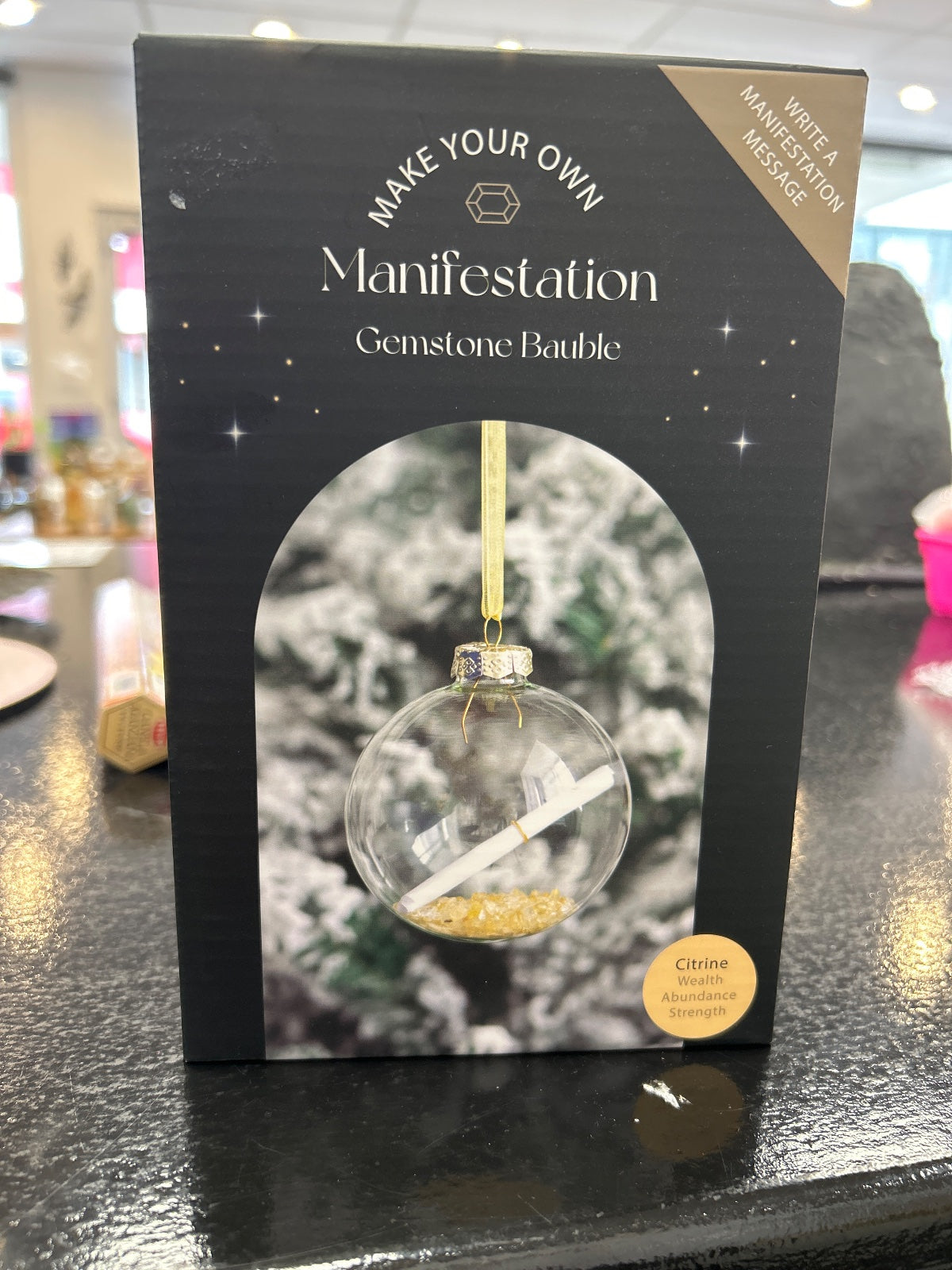 Make Your Own Manifestation Citrine Bauble in clear glass with gold trim and ribbon, on black packaging