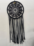 Black crochet dream catcher with intricate webbed mandala pattern and long black fringe strands