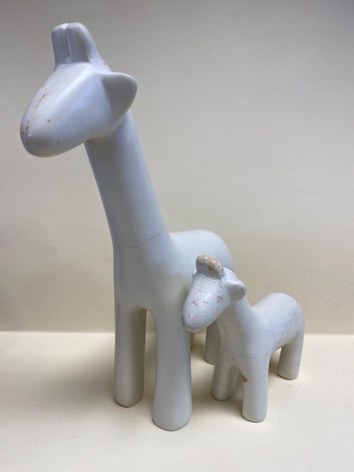 White ceramic giraffe and baby giraffe ornament set against neutral background