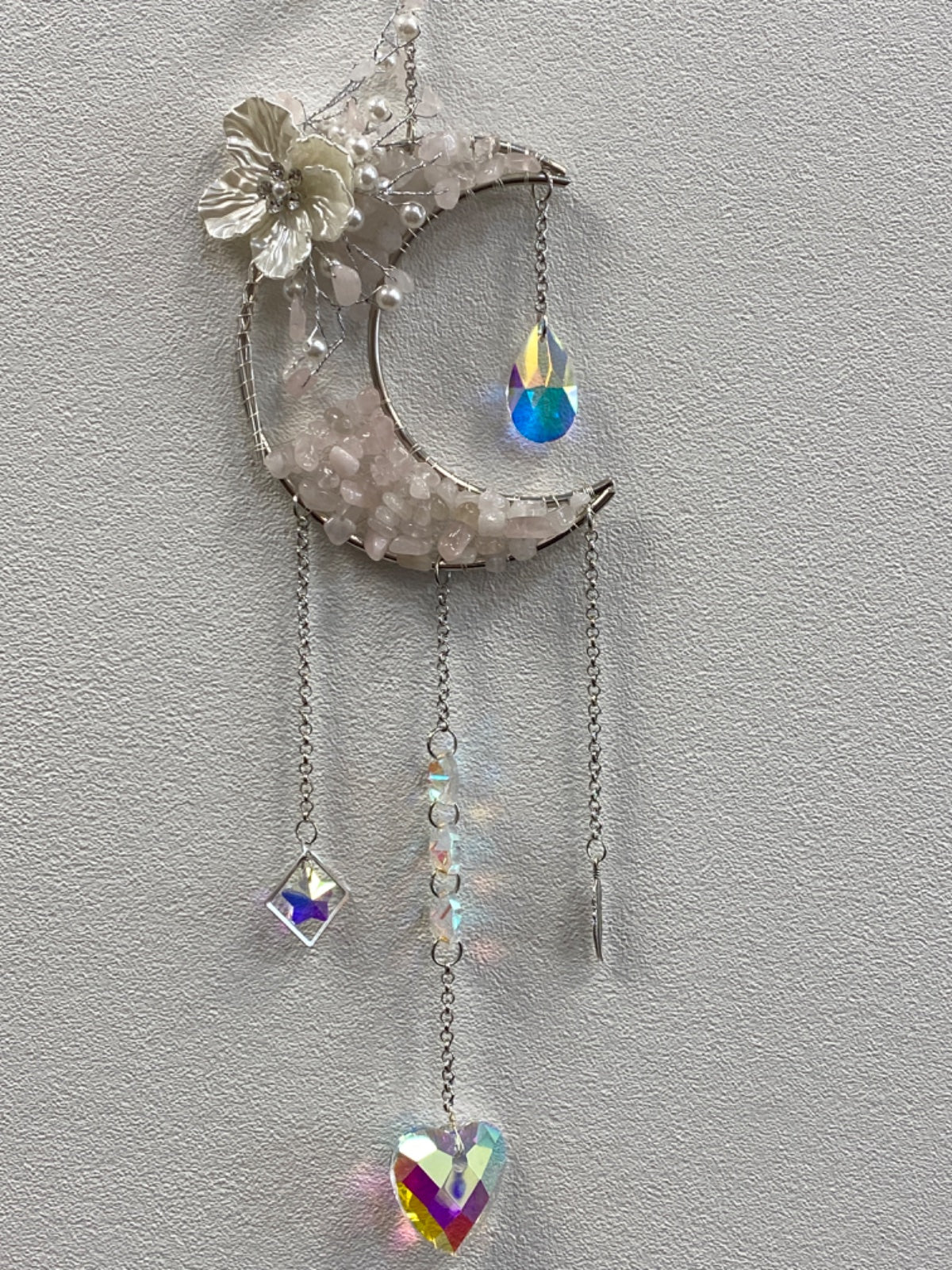Rose quartz crescent moon with flower accent and three hanging crystal pendants on chains