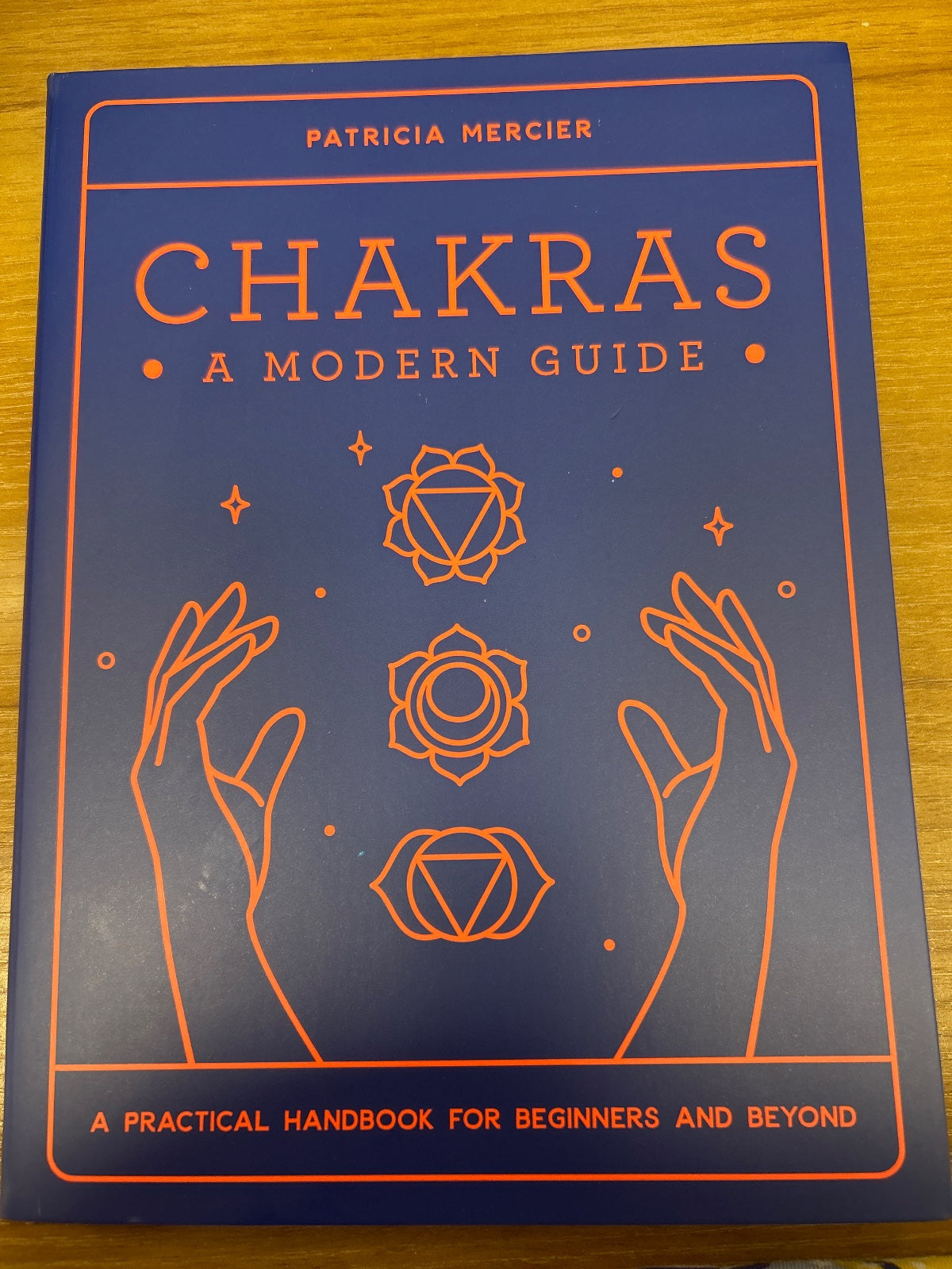 Chakras: A Modern Guide by Patricia Mercier, navy blue cover with orange line illustrations of hands and chakra symbols