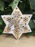 Wooden star ornament with laser-cut snowflake design, white painted finish with natural wood grain showing through