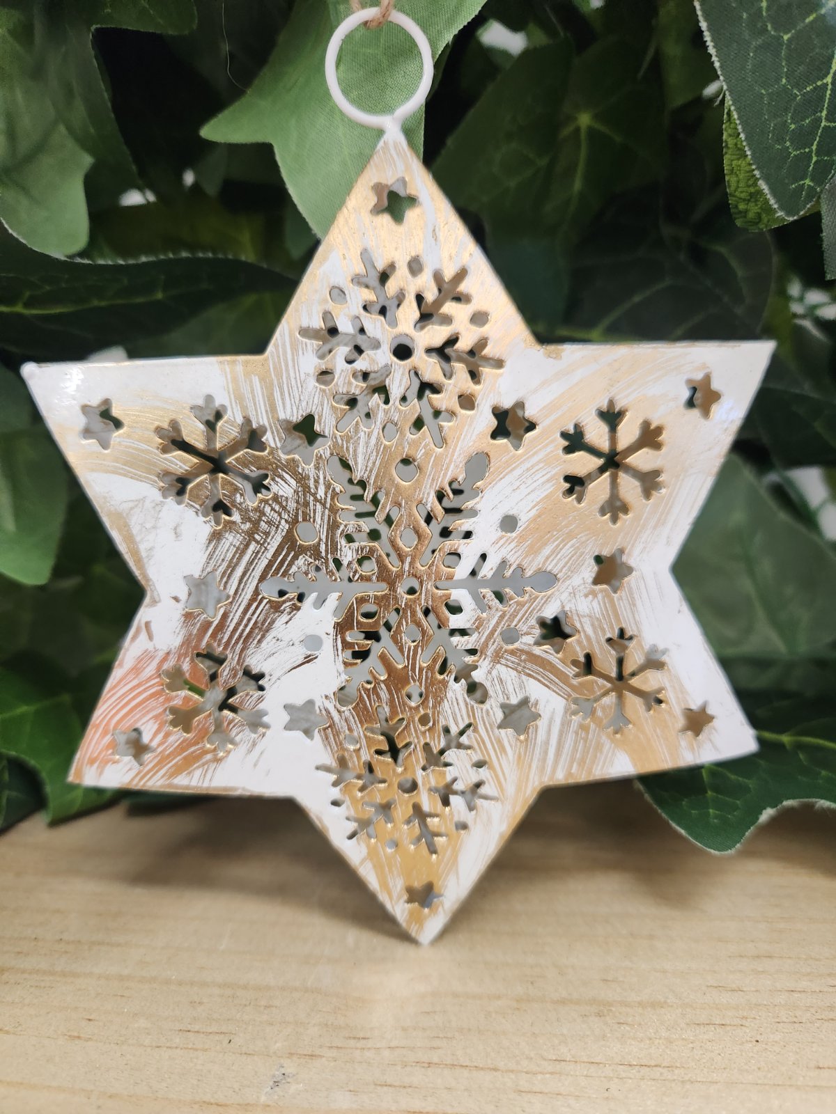 Wooden star ornament with laser-cut snowflake design, white painted finish with natural wood grain showing through