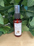 Magnesium and lavender spray in a dark red glass bottle with black pump cap and white label, surrounded by green leaves.