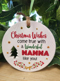 White ceramic round Christmas ornament with red and gold text reading 'Christmas Wishes come true with a Wonderful NANNA like you' decorated with gold stars, a green tree, and red berries