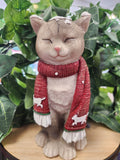 Grey and white ceramic cat figurine wearing a red knitted scarf with white trim and small cat motifs