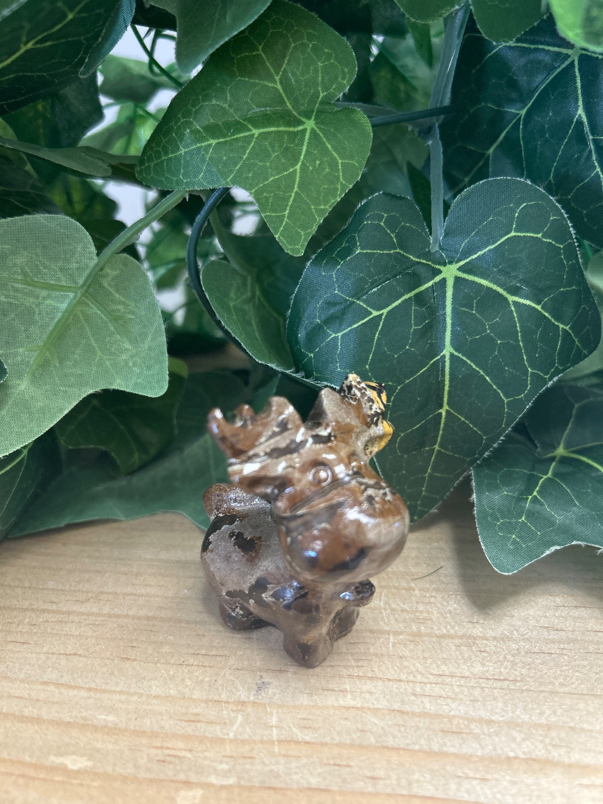 Picture Jasper reindeer figurine on wood with green leaves behind it