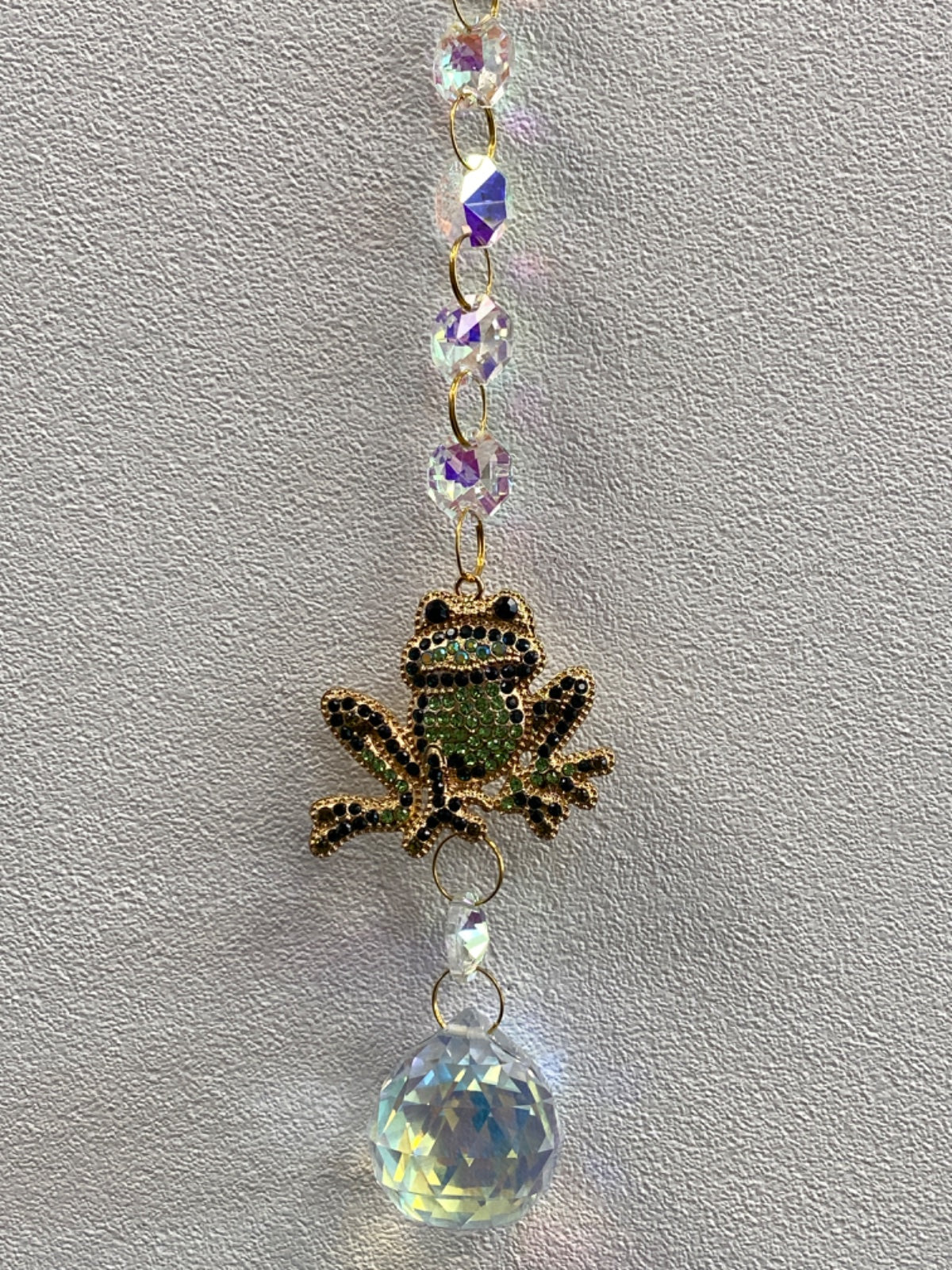 Decorative window hanger with purple faceted beads, gold-toned frog charm, and large clear crystal ball pendant