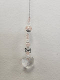 Pink beaded suncatcher with clear quartz heart charm, silver chain, and black bow accent