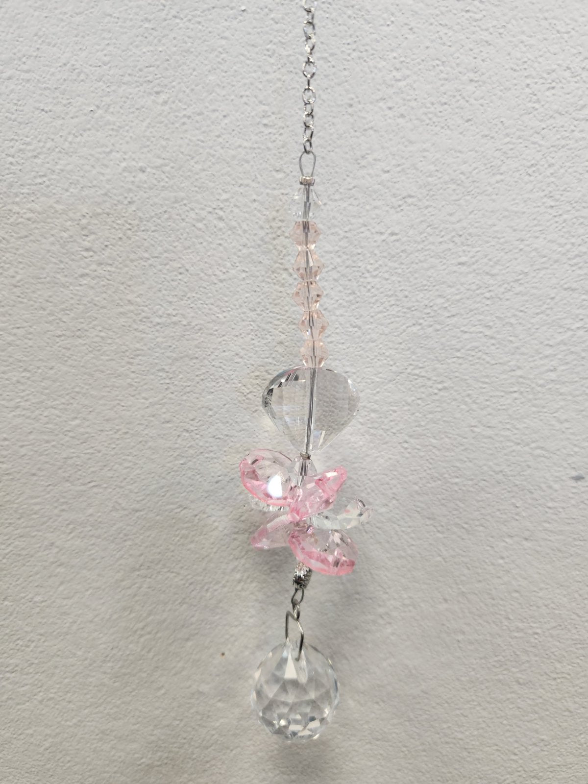 Pink beaded suncatcher with clear faceted charms hanging from a silver chain