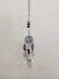 Silver chain hanger with purple amethyst beads, a blue and copper sun-moon face charm, and dangling star and crescent charms.