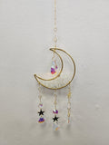 Gold half-moon suncatcher with clear quartz, rainbow crystals, and black stars hanging from chains