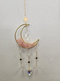 Brass crescent moon suncatcher with pink strawberry quartz, gold chain, crystal prisms, and hanging star charms
