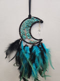Moon-shaped dreamcatcher with turquoise chip stones, black wire frame, copper wire detail, hanging crystal, and layered turquoise and black feathers