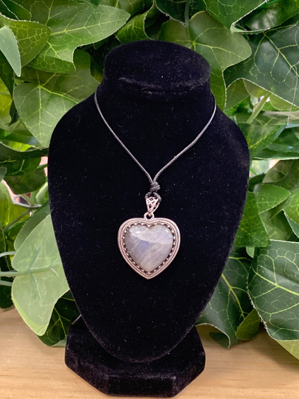 Labradorite heart pendant with beaded silver frame on black cord, displayed on black velvet bust.
