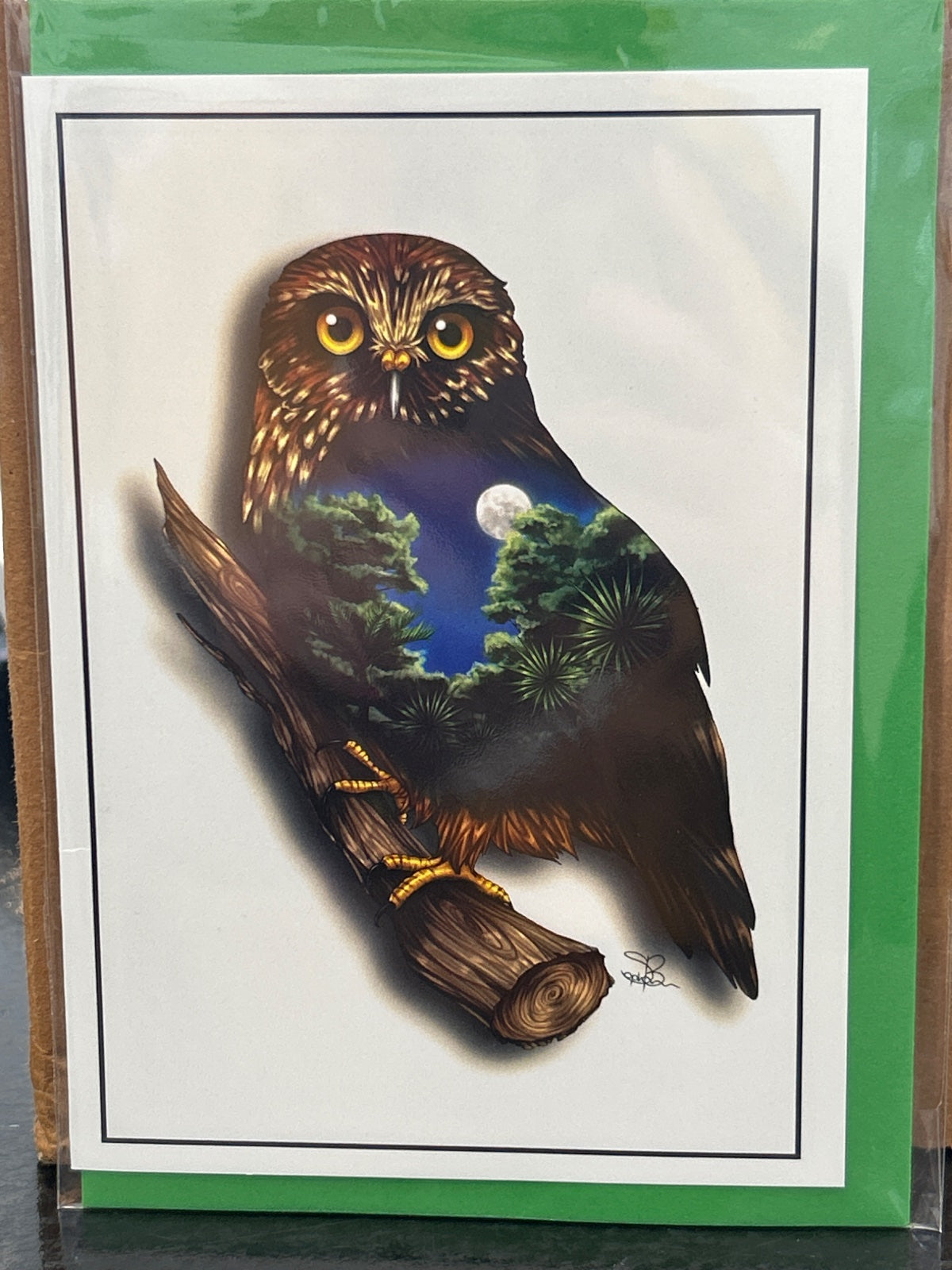 Greeting card featuring a brown morepork owl perched on a branch, with a nighttime forest scene visible within its body silhouette