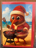 Cartoon Santa kiwi bird in red suit grilling sausages on a beach.