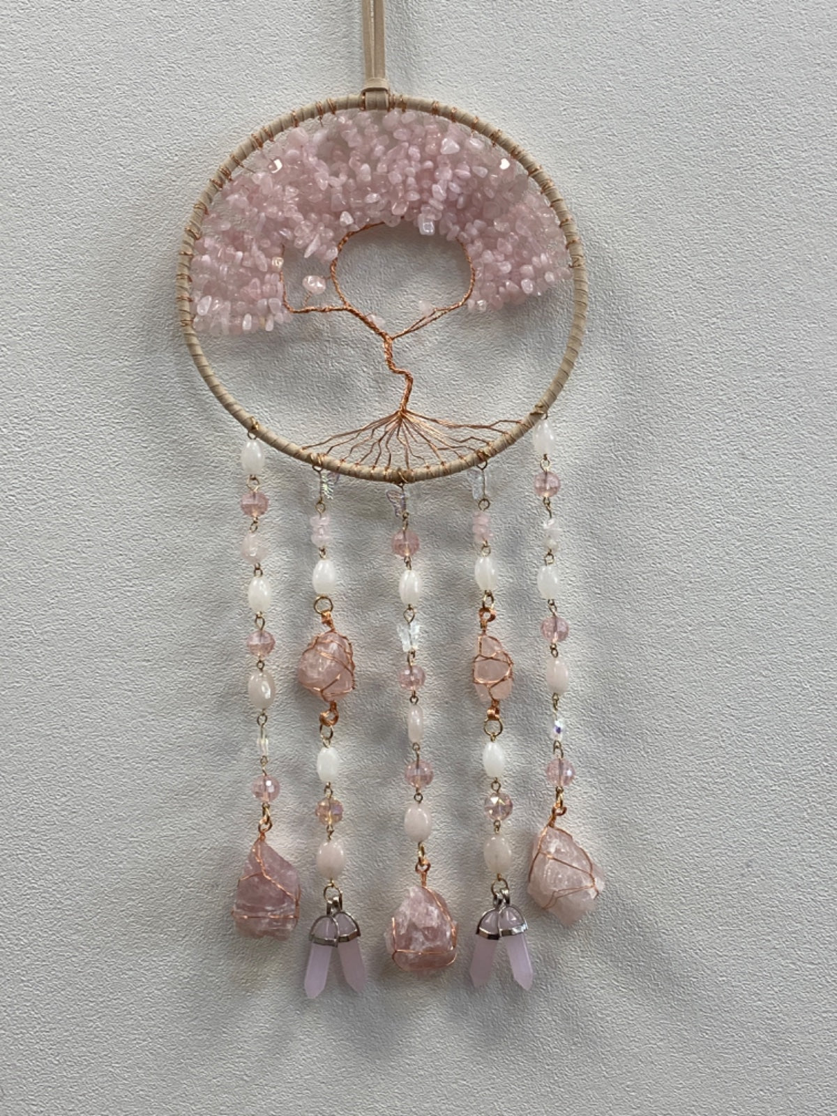 Rose Quartz Chip Tree of Life wall hanger with raw and polished stones, cream beads, and copper wire on jute cord.