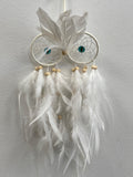 White feather owl dreamcatcher with turquoise eyes, intricate web detailing, and hanging white feather strands with wooden beads.