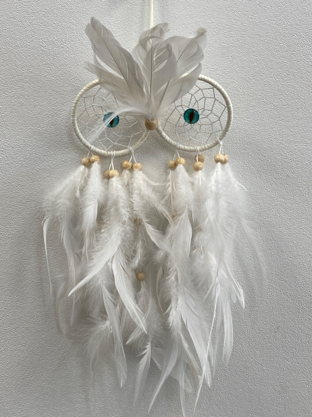 White feather owl dreamcatcher with turquoise eyes, intricate web detailing, and hanging white feather strands with wooden beads.