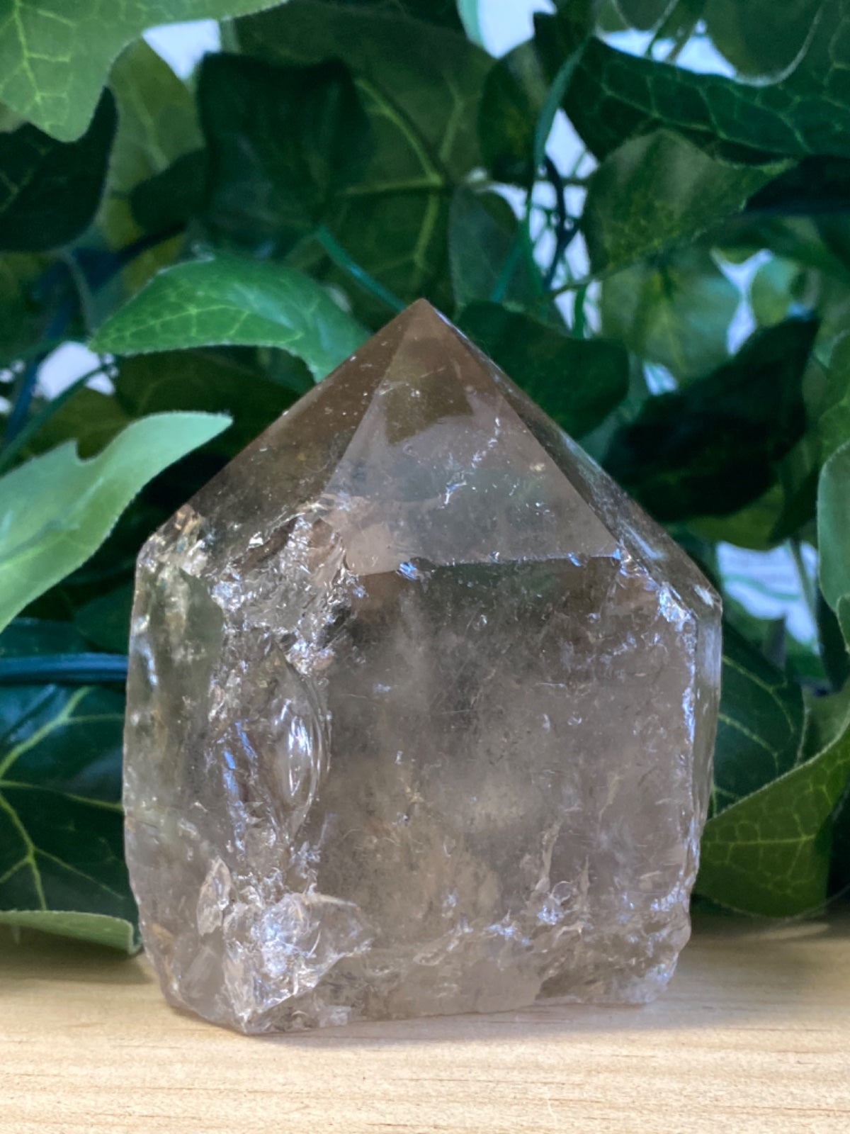 Raw smoky quartz point, roughly 10cm tall, pale grey-brown with natural facets and cloudy inclusions