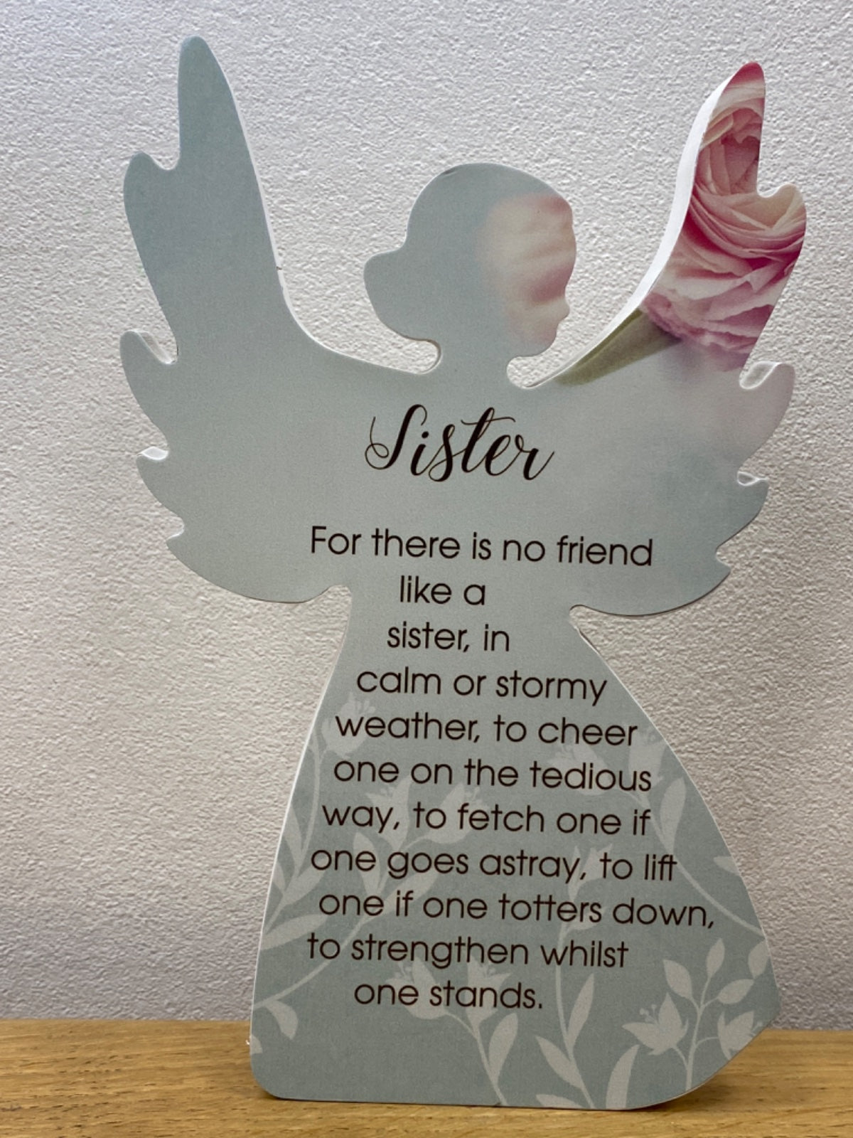 White angel figurine plaque with poem text, pink flower detail on right wing, standing on wooden surface