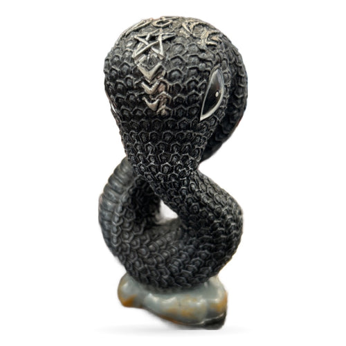 Black carved snake sculpture with pagan symbols and pale stone base