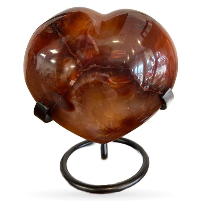Polished carnelian heart-shaped crystal 490g on black metal stand, reddish-brown translucent
