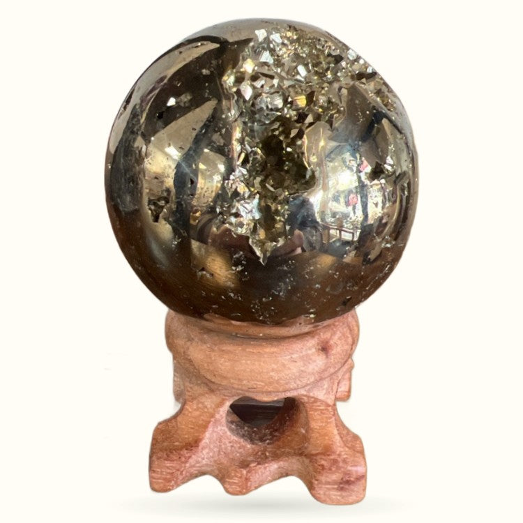 Pyrite sphere on wooden stand showing metallic gold surface with natural cubic crystal formations