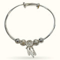 Silver dreamcatcher bracelet with filigree beads and dangling feather charms on bangle