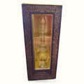 Purple ornate box containing glass fragrant oil bottle with rose-colored liquid and flame-shaped stopper