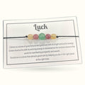 Luck bracelet with five polished gemstone beads on black cord with informational card