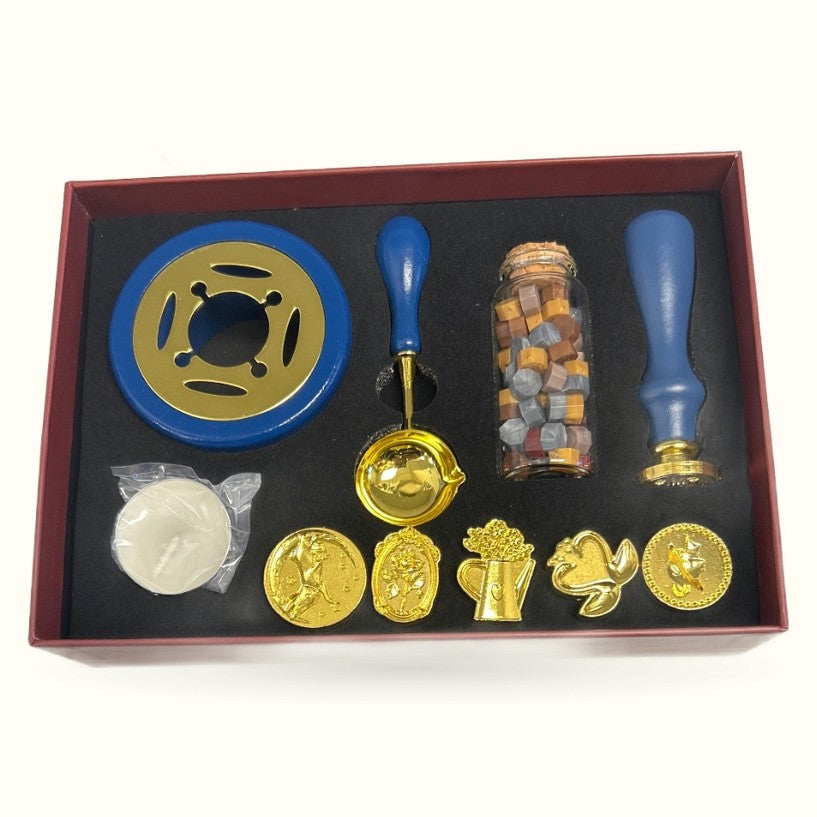 Wax seal stamp set in burgundy box containing blue handles, gold seals, wax sticks, and decorative stamps