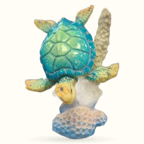Blue and green decorative turtle figurine perched on white and blue textured coral base