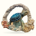 Blue turtle figurine with dark shell positioned in round coral reef sculpture display