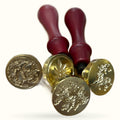Wax stamp set with four brass seal stamps and burgundy wooden handles