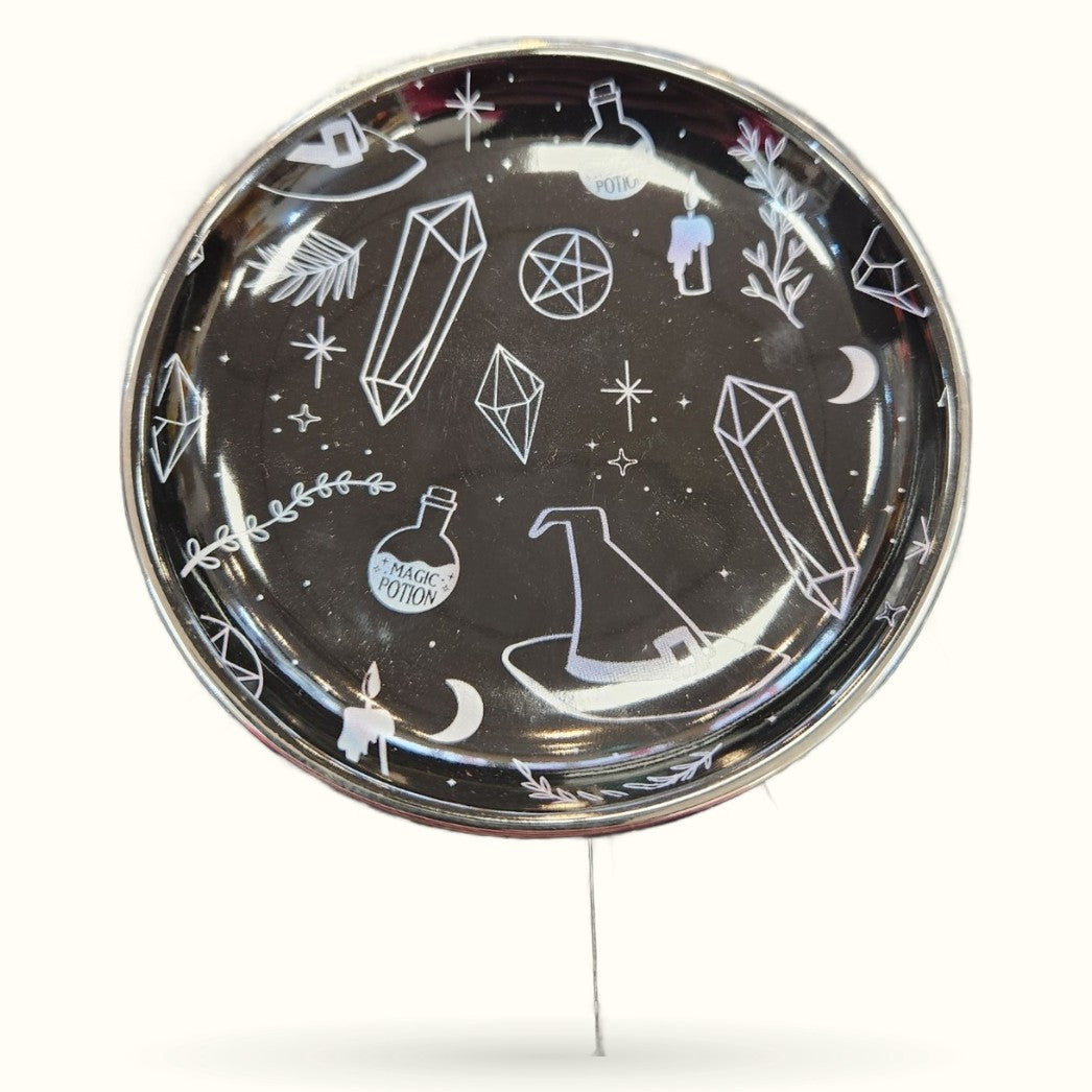 Black circular trinket dish with white witchy illustrations including crystals, potion bottles, moons, and stars