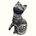 Black ceramic cat ornament sitting upright with decorative collar and patterned belly, 12cm tall