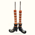 Pair of resin witch leg planters with black shoes, orange and white striped stockings, and gray stem candle holders