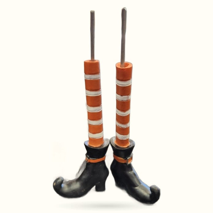 Pair of resin witch leg planters with black shoes, orange and white striped stockings, and gray stem candle holders