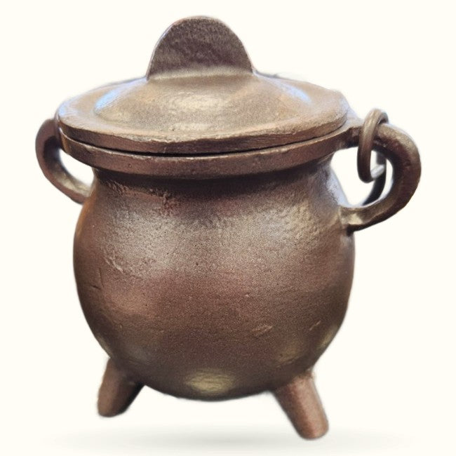 Small bronze pewter cauldron with lid, three feet, and decorative handles on white background