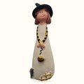 Resin witch figurine with brown hair, black hat, cream robe, yellow and black snake necklace holding gold pumpkin