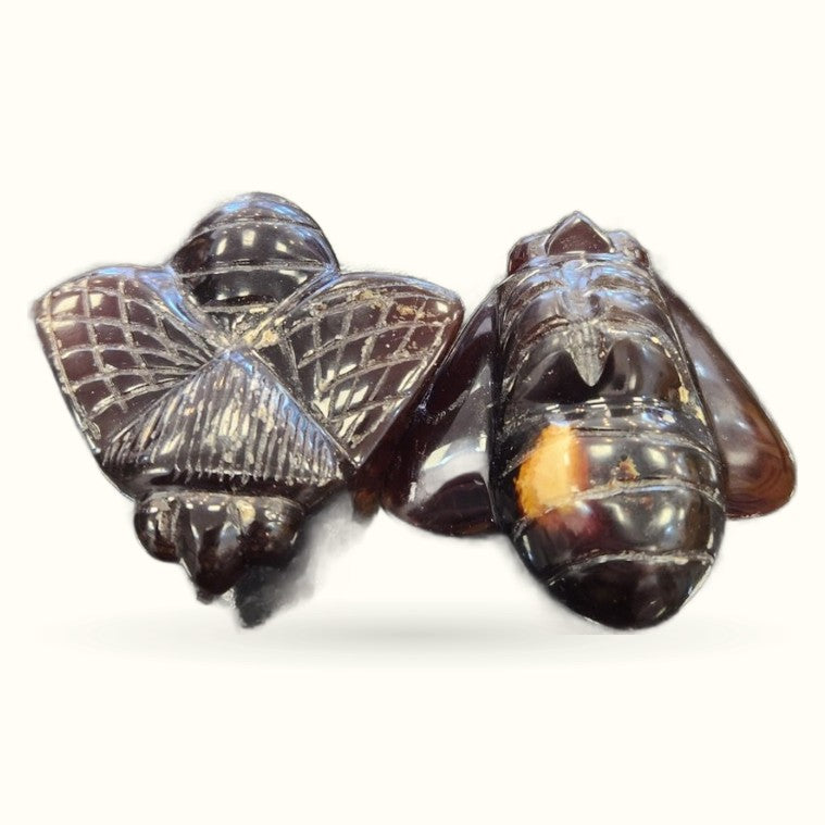 Three carved amber bee figurines with detailed wings and segmented bodies, polished finish