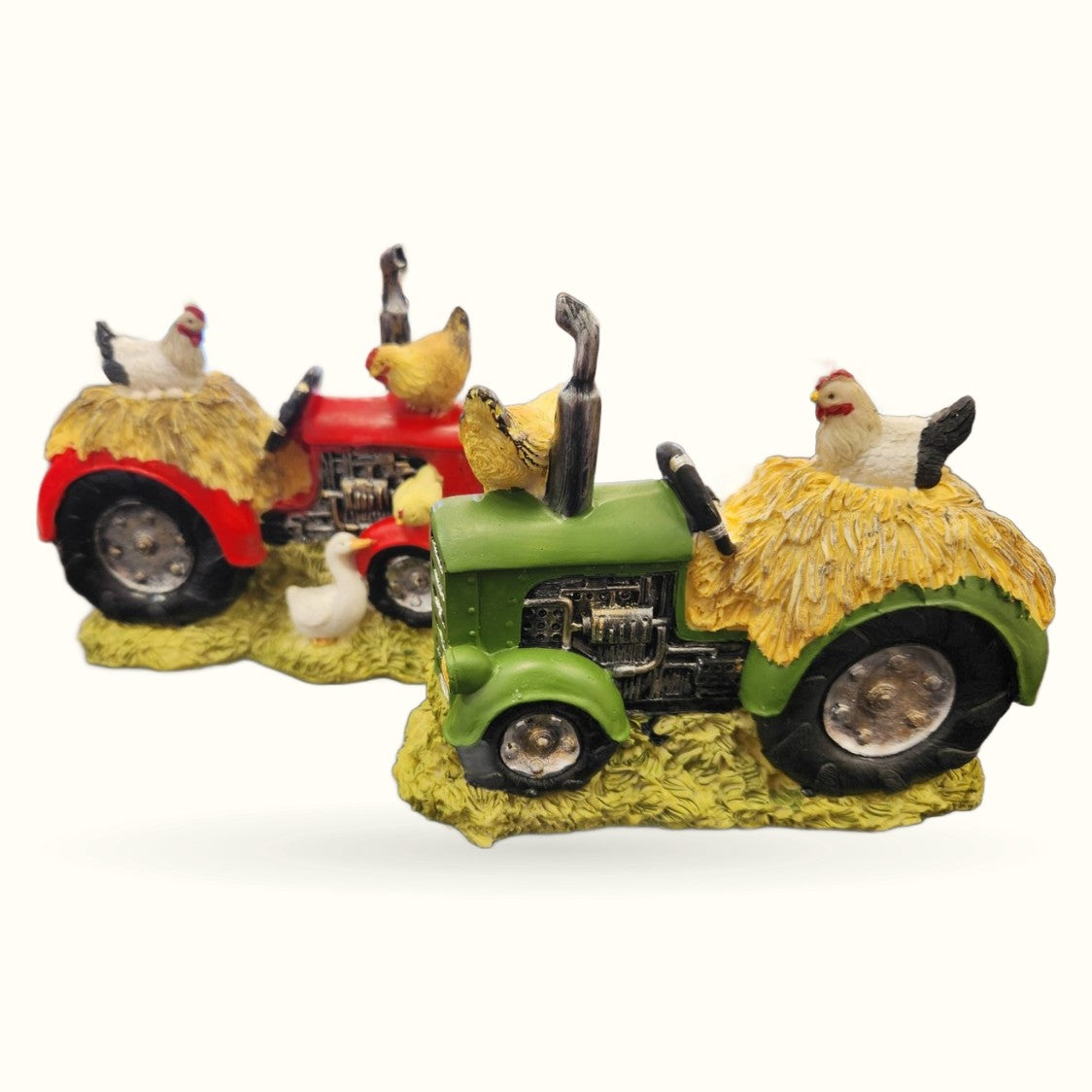 Three colorful farmyard tractor ornaments with chickens and straw, featuring red, green and yellow tractors