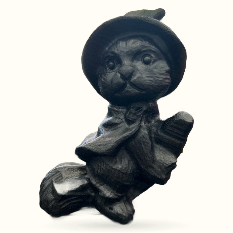 Black obsidian carved witch cat wearing a hat and sitting on a broomstick