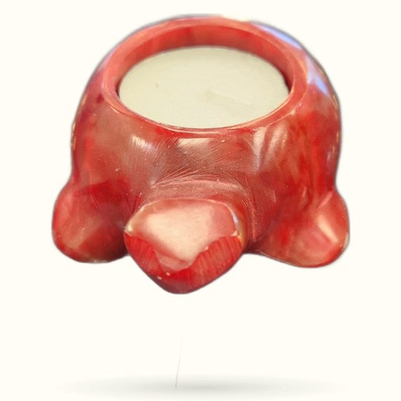 Red turtle-shaped candle holder with cream-colored candle inside, glossy finish